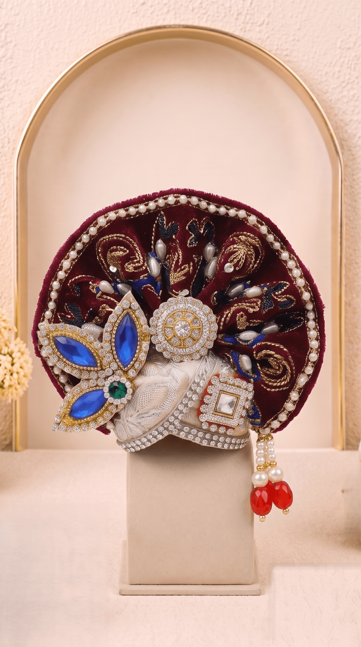 Designer mukut from the Rajsi Shyam Set featuring burgundy fabric, blue embellishments, pearl detailing, gold embroidery and handcrafted peacock-inspired accents